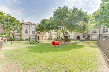 A playground area with a swing set and a slide in a grassy yard.